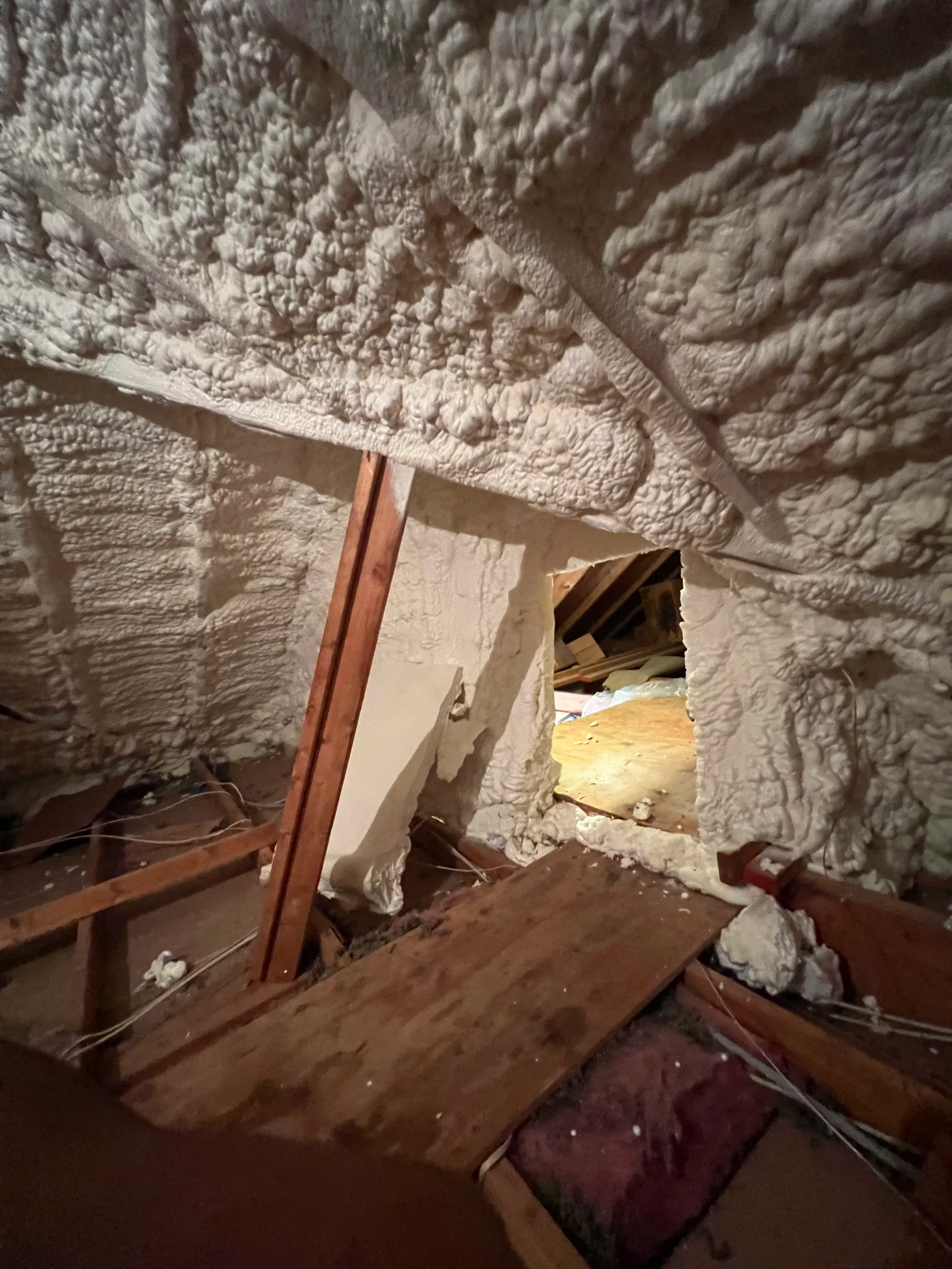 Spray foam insulation covering ceiling and walls with textured finish around steel beam framing